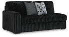 Black ribbed fabric loveseat with two throw pillows. One pillow is gray textured, the other is black and white with a geometric pattern.