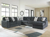 Large U-shaped dark gray sectional sofa with plush ribbed corduroy-like fabric and assorted throw pillows, including patterned and solid gray, in a modern living room with large windows and a geometric rug.