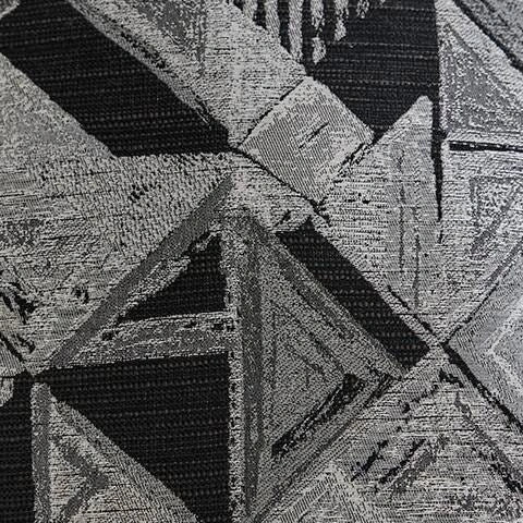 Close-up of a woven fabric swatch featuring an abstract geometric pattern with triangles and rectangles in shades of black, dark grey, and light grey. The texture shows visible threads.