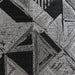 Close-up of a woven fabric swatch featuring an abstract geometric pattern with triangles and rectangles in shades of black, dark grey, and light grey. The texture shows visible threads.