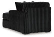Black armless chair with plush, vertically ribbed upholstery. The back and side panels feature prominent vertical channels, and it rests on dark, low-profile block feet.