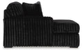 Black chaise lounge upholstered in a soft, channel-tufted plush fabric. It features a single armrest, a deep seat, and a matching back cushion.