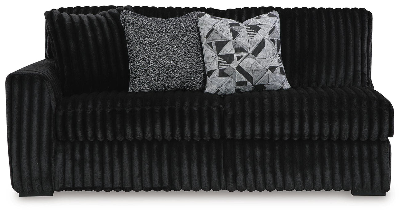 Black ribbed sofa with two throw pillows: one gray textured, one black and white geometric.