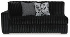 Black ribbed sofa with two throw pillows: one gray textured, one black and white geometric.