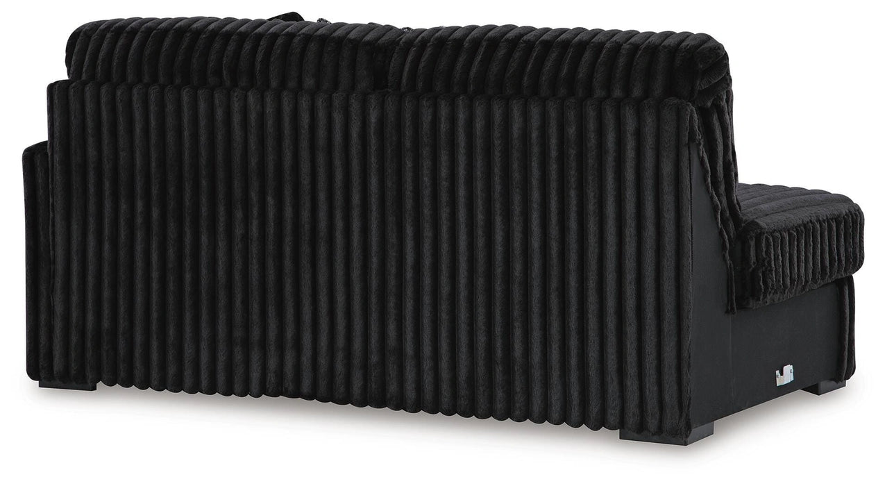 Black modern sofa with plush, vertically ribbed fabric on the back and seat cushions, viewed from the back and side on a white background.