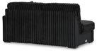 Black modern sofa with plush, vertically ribbed fabric on the back and seat cushions, viewed from the back and side on a white background.