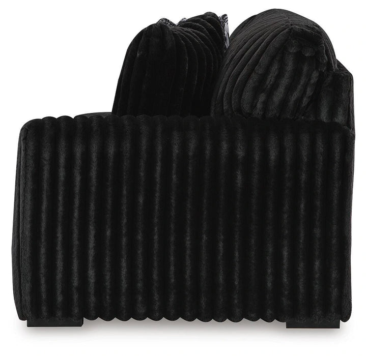 Black plush accent chair with a distinctive vertically ribbed texture on its base and back, featuring two soft, rounded back cushions.