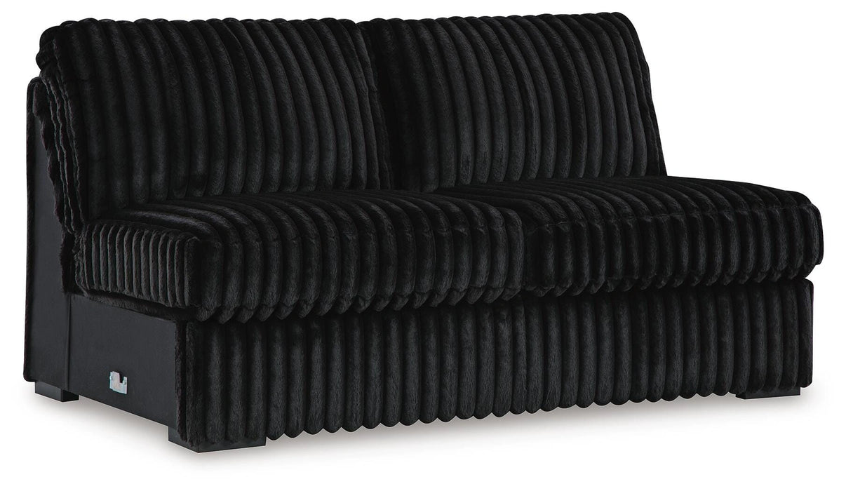 Black modular armless chair upholstered in plush ribbed velvet fabric, featuring channel-tufted back and seat cushions and low dark feet.