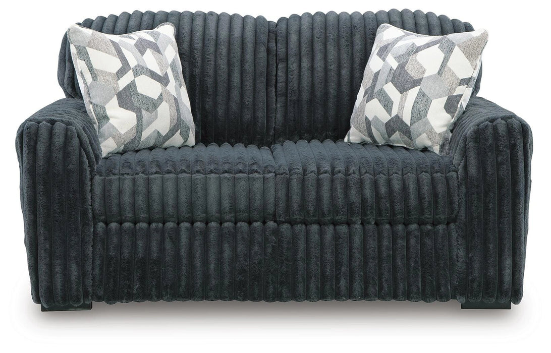 Dark gray plush ribbed sofa with two decorative throw pillows featuring a geometric pattern in white, gray, and black.