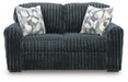 Dark gray plush ribbed sofa with two decorative throw pillows featuring a geometric pattern in white, gray, and black.