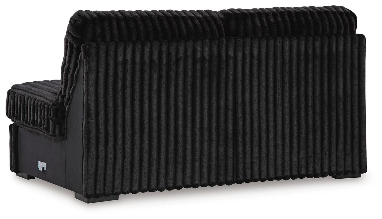 Black modular sofa section, shown from the rear three-quarter view. It is upholstered in a plush, vertically ribbed fabric that covers the back and visible side. The lower frame is smooth black, and it stands on dark, low-profile square feet.