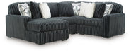 Dark gray L-shaped sectional sofa with plush, ribbed corduroy upholstery. Includes two white faux fur throw pillows and two gray and white geometric patterned pillows.
