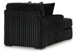 Black armchair upholstered in plush, vertically channeled fabric, with square arms and dark block feet, viewed from the back-side.