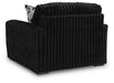Black armchair with plush, vertically channeled fabric on the back and sides, and a patterned throw pillow visible.
